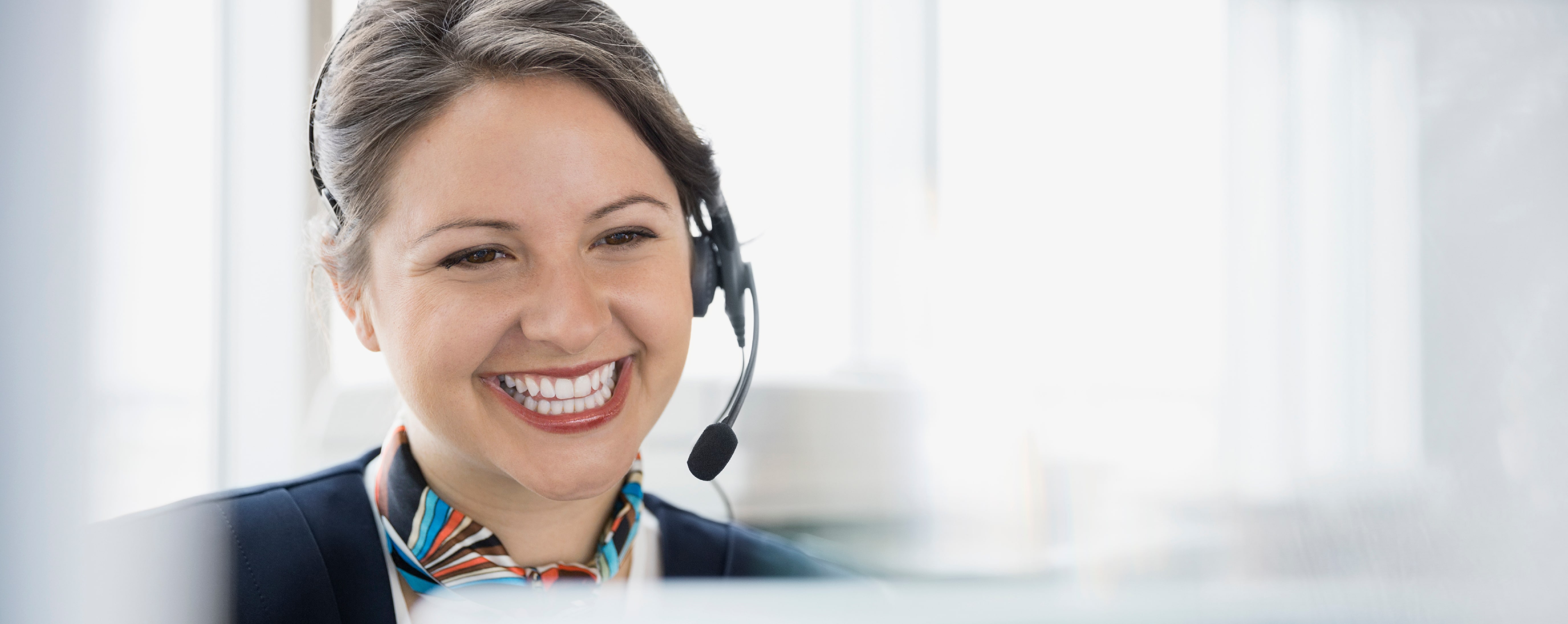 Smiling female call center employee wearing a headset while answering a call.